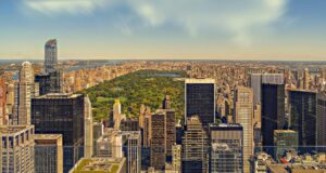 Aerial view of New York City skyline featuring Central Park amidst towering skyscrapers.